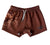 Little Windmill Dust Scene Bull Footy Shorts. Person wearing brown shorts with a pattern and visible brand logo, standing outdoors.