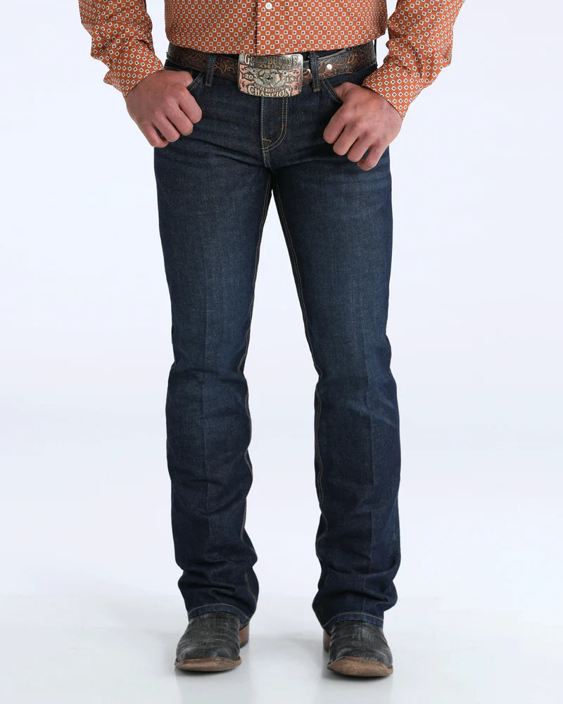 Person wearing dark blue jeans with a patterned shirt and belt on a white background