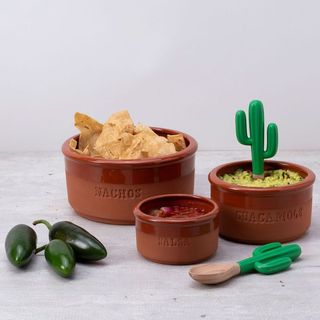 Monkey Business Bowlero Mexican Snack Bowls. Set of terracotta bowls with 'Nachos' and 'Guacamole' text, accompanied by tortilla chips, jalapenos, and a cactus-shaped container on a light gray background.
