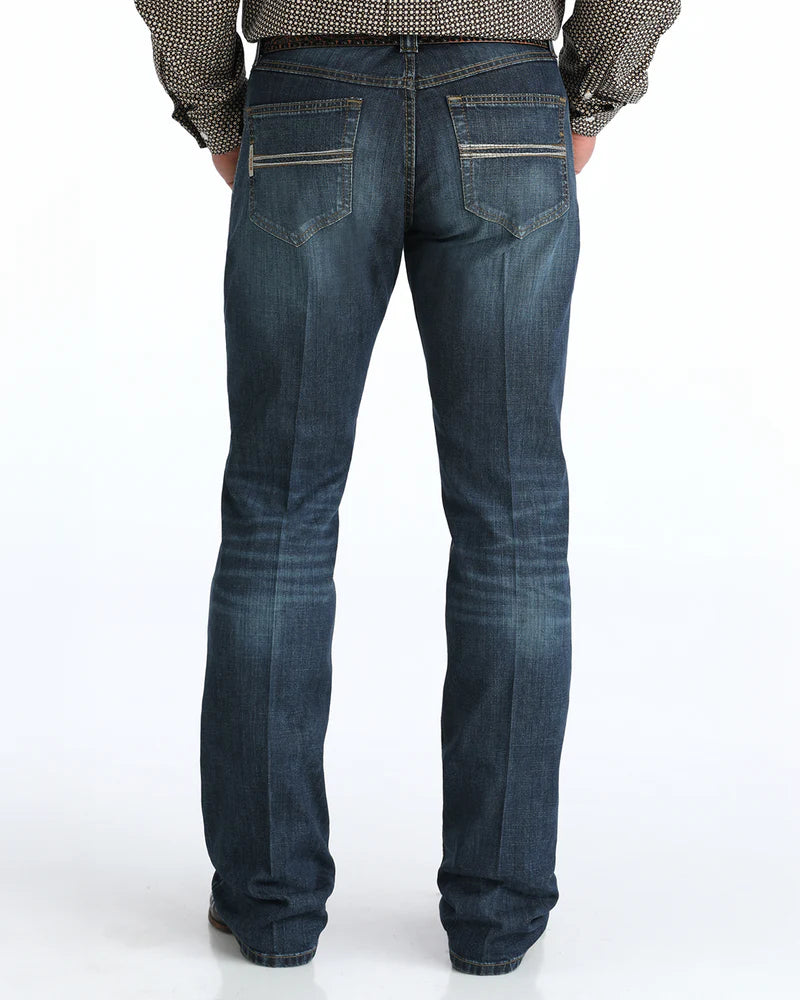 Person wearing blue jeans with a patterned shirt and belt on a white background