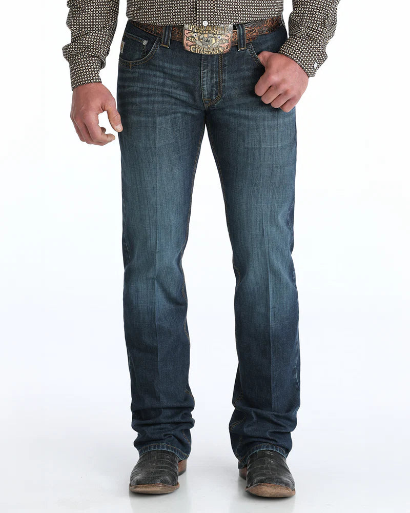 Person wearing blue jeans with a patterned shirt and belt on a white background