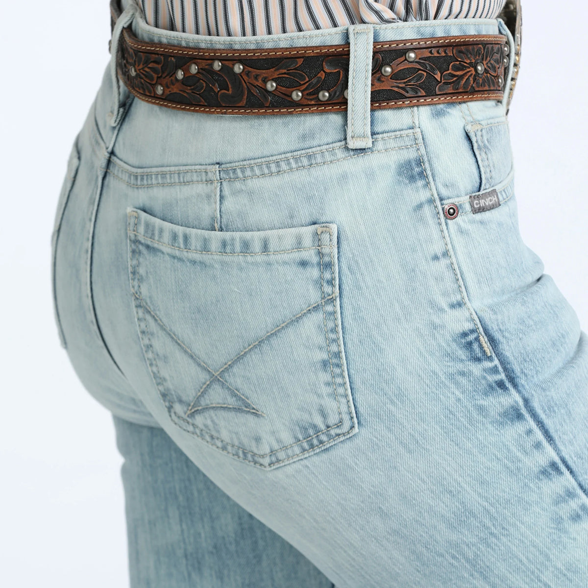 Light blue jeans with a decorative brown belt on a white background