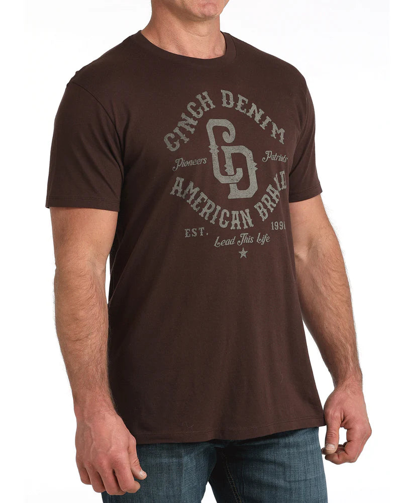 Man wearing a brown t-shirt with 'Cinch Denim American Brand' logo on a white background