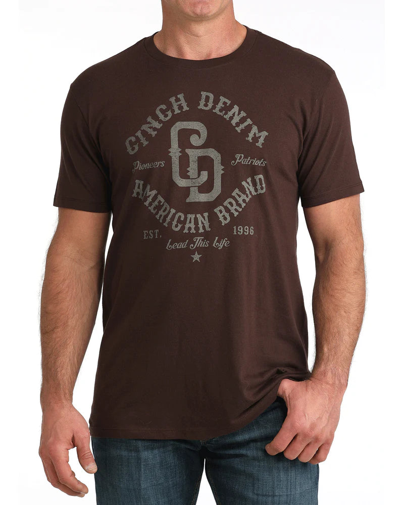 Man wearing a brown t-shirt with 'Cinch Denim American Brand' logo on a white background
