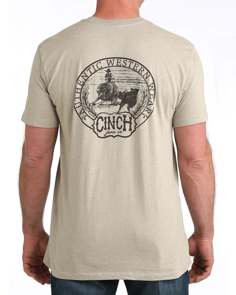 Beige t-shirt with Cinch logo on the back, worn by a person