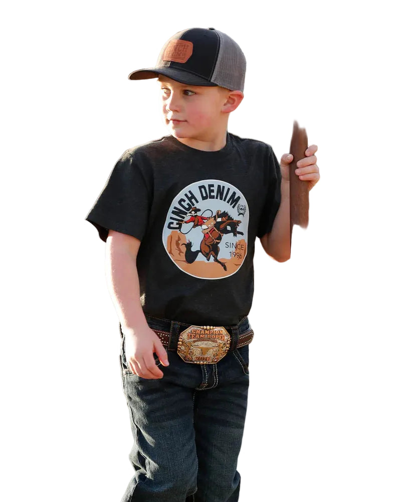 Child wearing a black t-shirt with 'Ginch Denim' logo, standing in an outdoor setting.