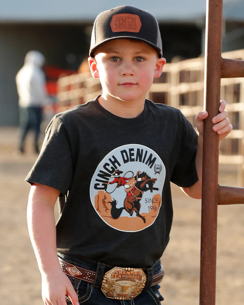 Child wearing a black t-shirt with 'Ginch Denim' logo, standing in an outdoor setting.