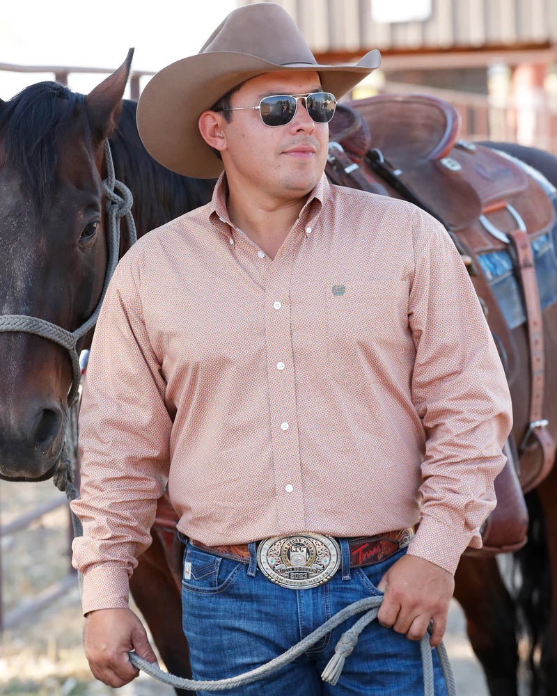 Cinch Men's Stretch Classic Fit Button-Down Western Shirt. Man in cowboy hat and sunglasses standing next to a horse, wearing a patterned shirt and blue jeans.