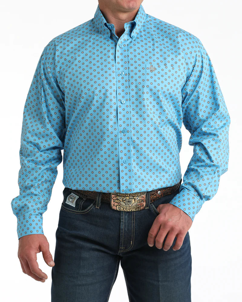 Man wearing a light blue patterned shirt and dark jeans on a white background