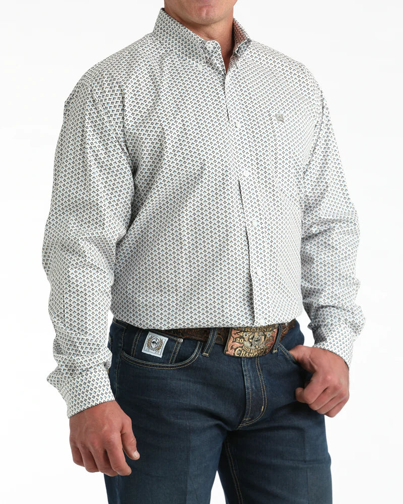 Man wearing a white patterned shirt and dark jeans on a white background