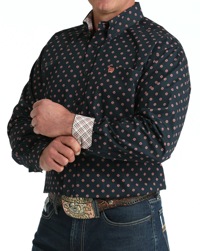 Man wearing a dark patterned shirt with rolled-up sleeves on a white background