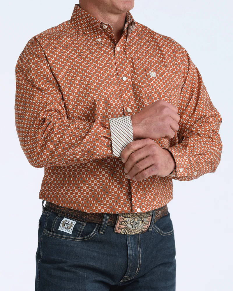Man wearing a patterned brown shirt with a visible brand logo on a white background