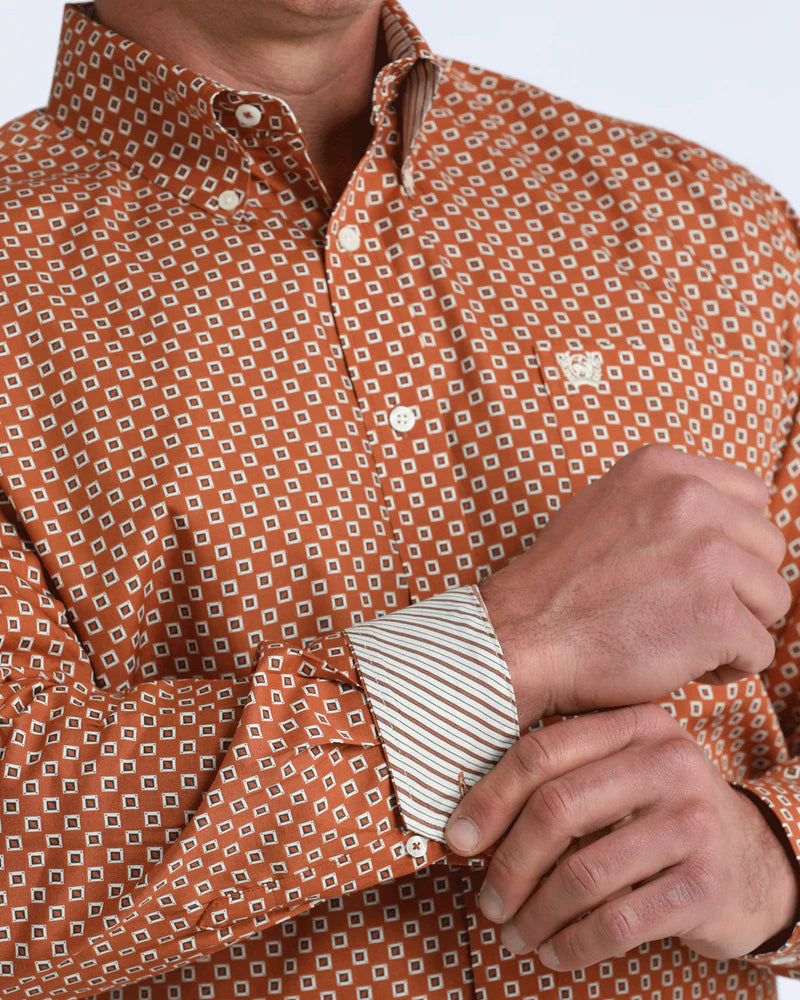 Man wearing an orange patterned shirt holding a deck of cards.