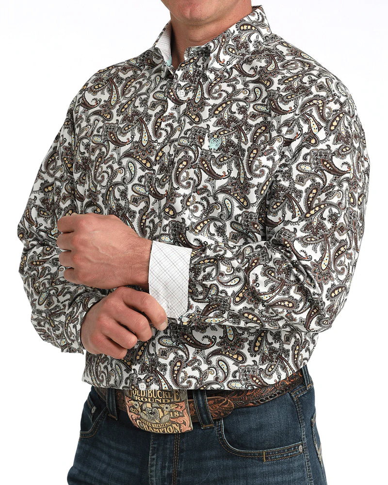 Man wearing a patterned shirt and jeans with a belt on a white background