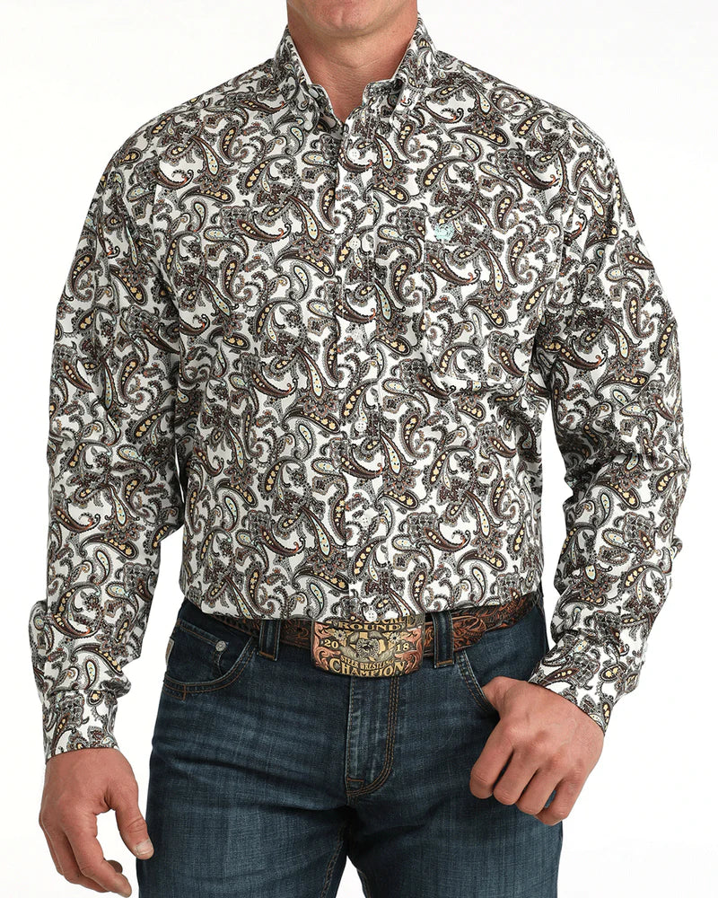 Man wearing a patterned shirt and jeans with a belt on a white background