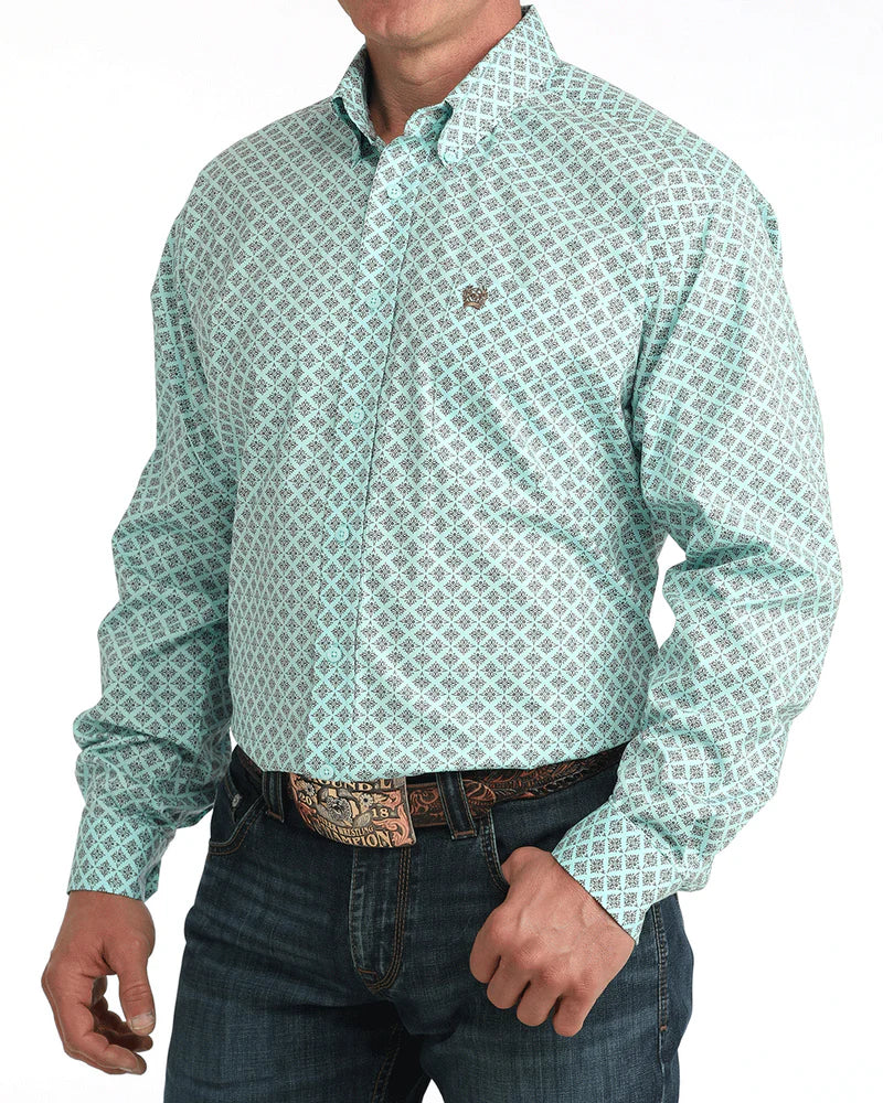 Man wearing a green patterned shirt and jeans on a white background