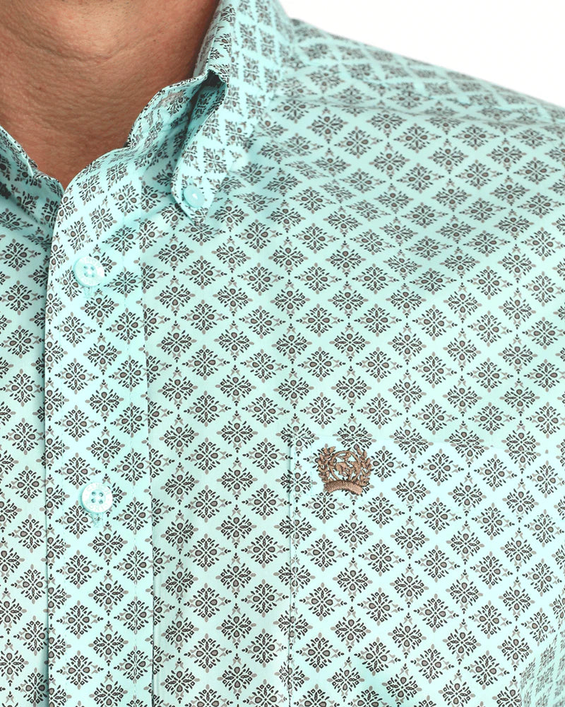 Close-up of a light blue patterned shirt with a small emblem on a white background