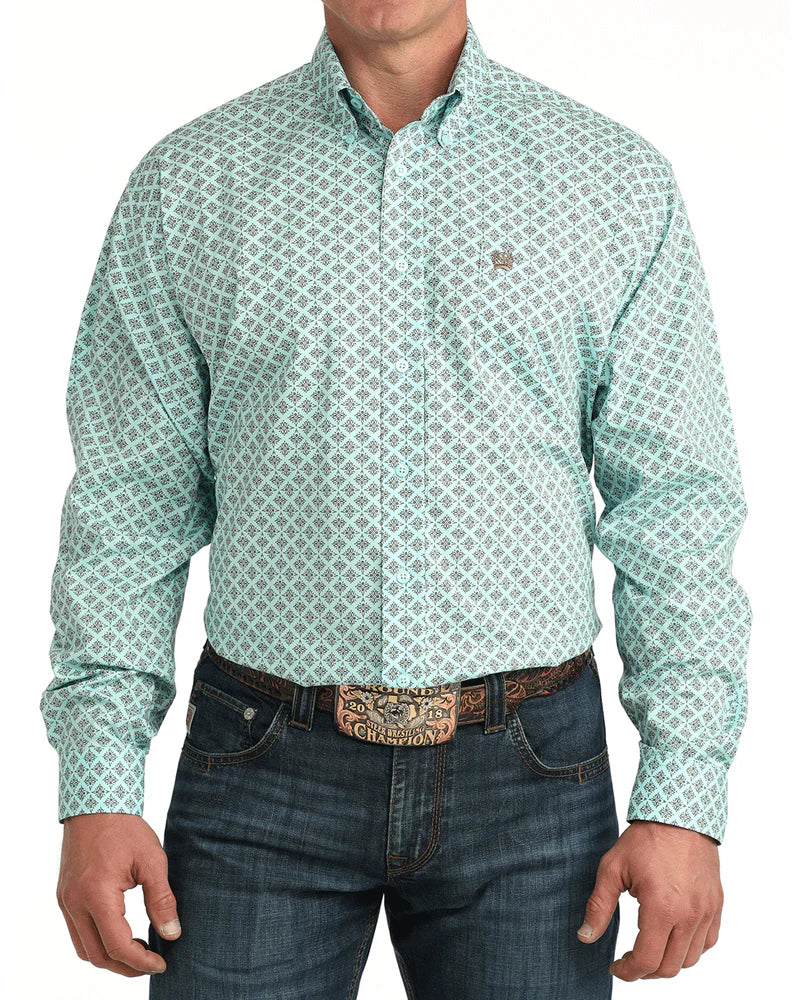 Man wearing a green patterned shirt and jeans on a white background