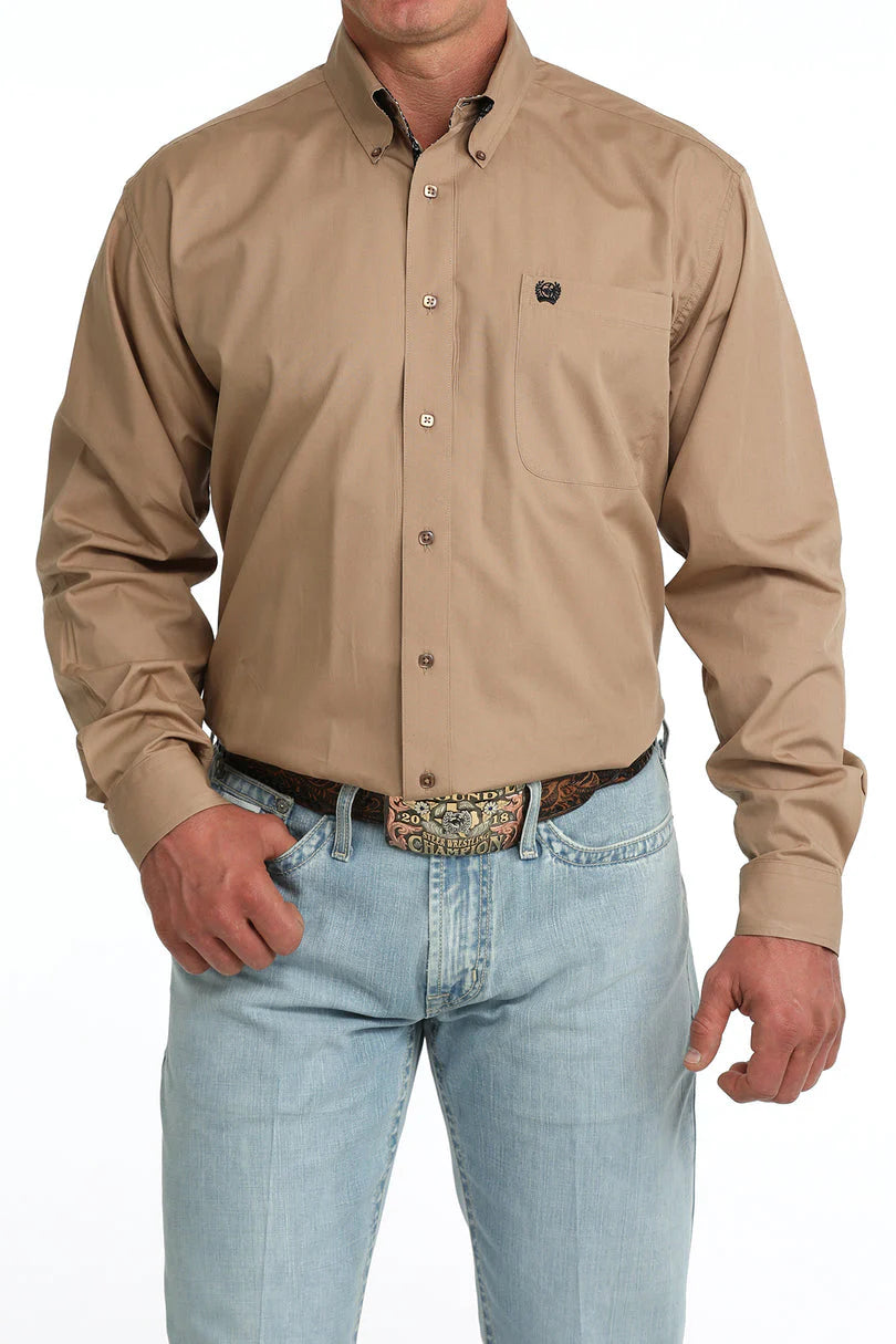 Man wearing a beige button-up shirt and light blue jeans on a white background