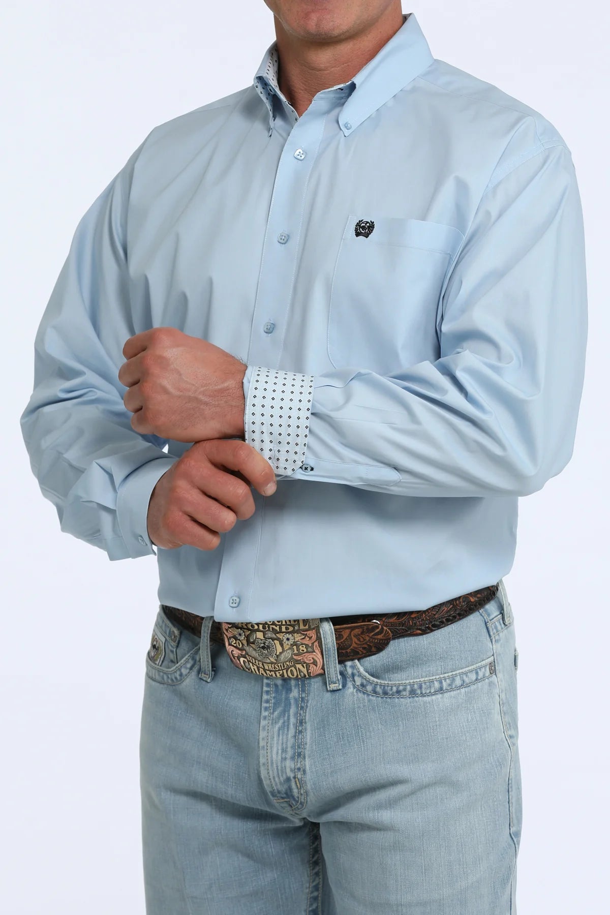 Light blue button-up shirt with decorative cuffs and jeans on a white background