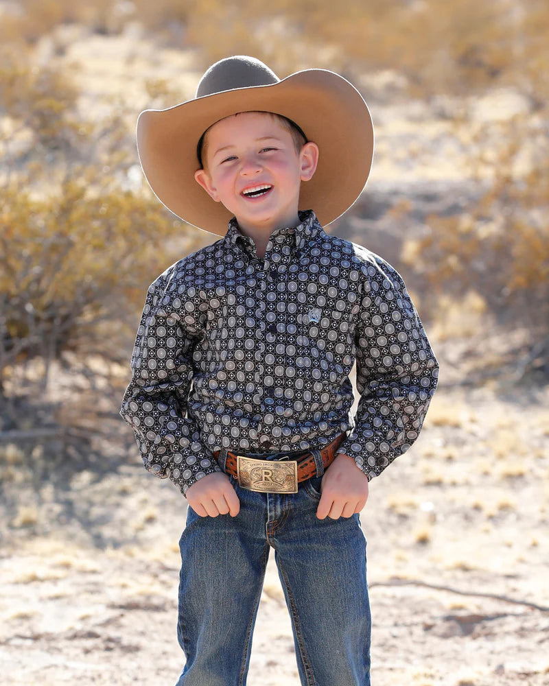 Child wearing a cowboy hat and patterned shirt in a desert setting