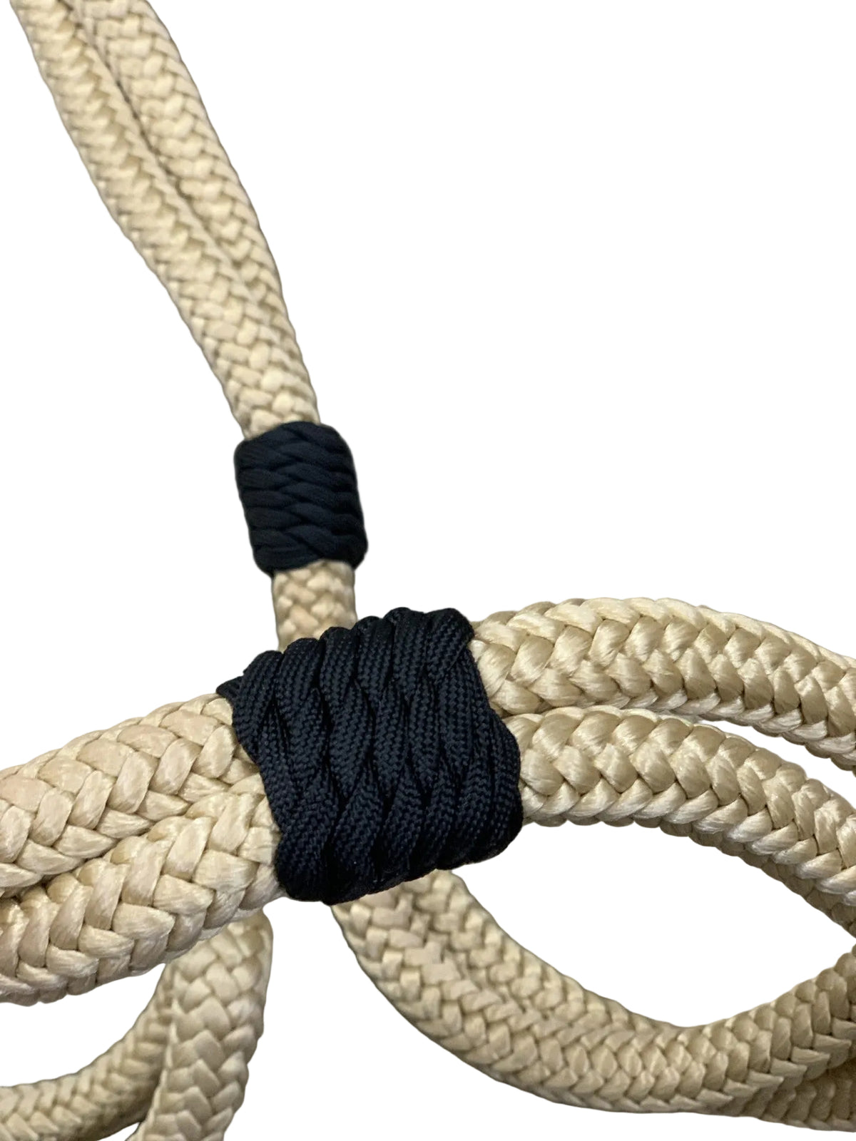 Close-up of beige rope with black cord tied around it on a concrete surface