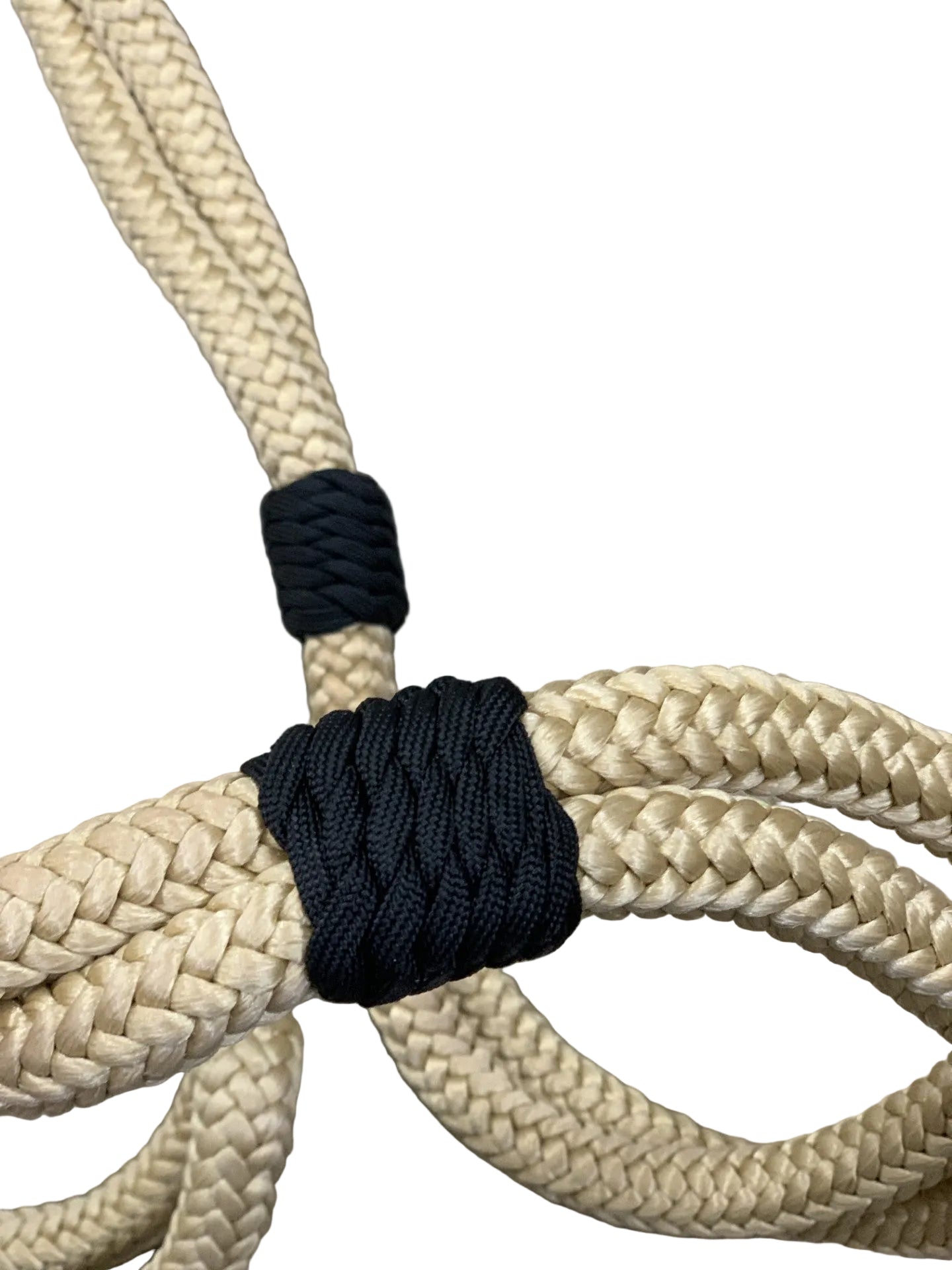 Close-up of beige rope with black cord tied around it on a concrete surface