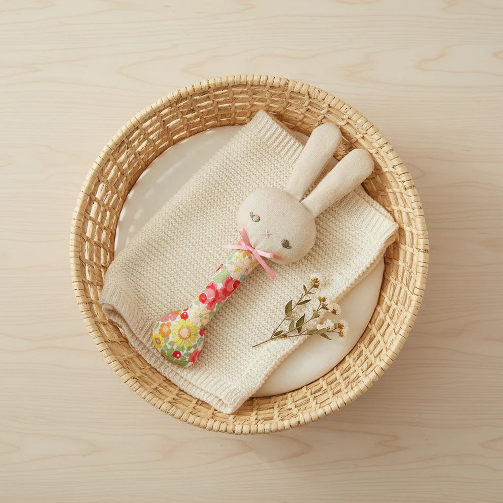 Stuffed bunny toy with floral handle on a white background