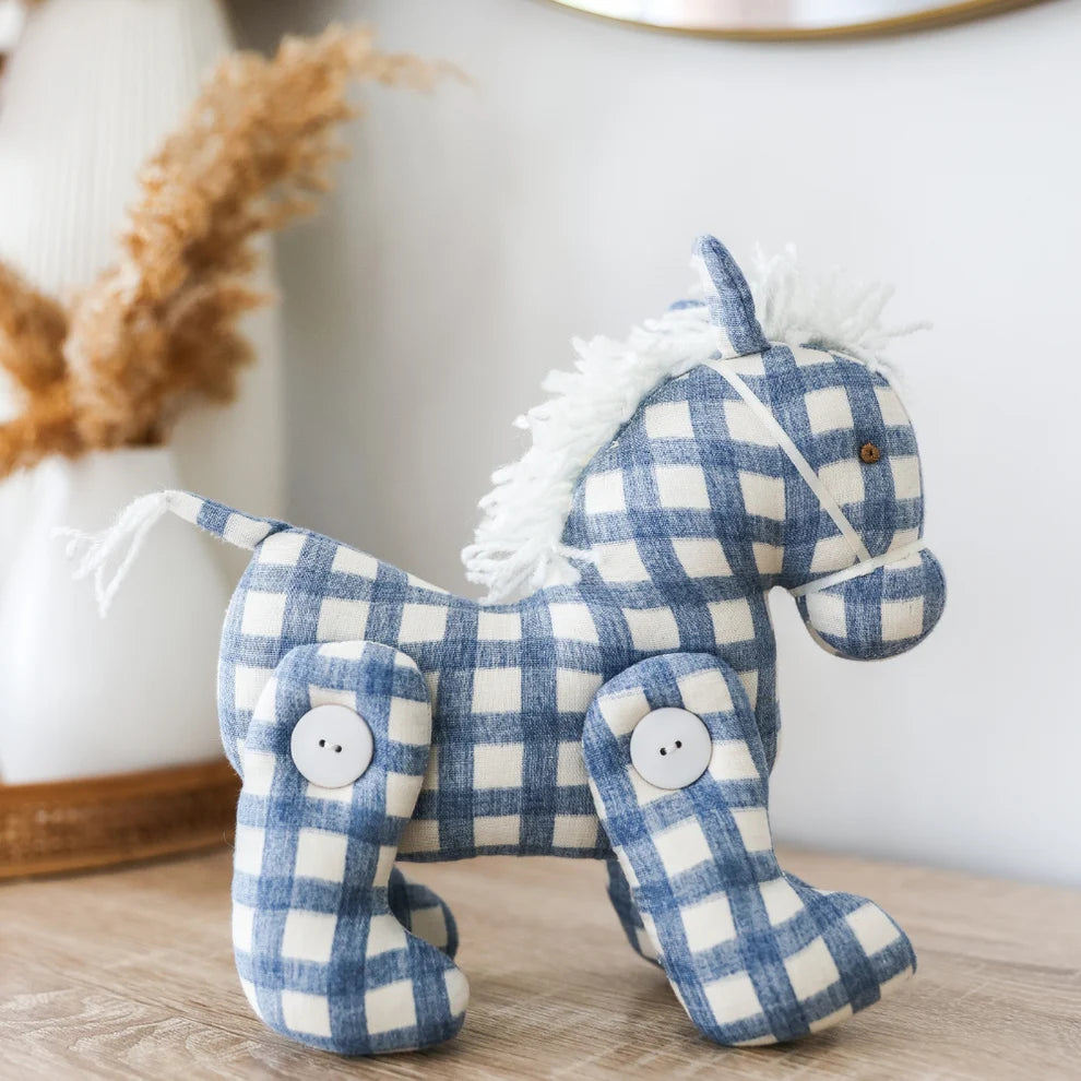 Blue and white checkered plush horse toy on a wooden surface with a neutral background
