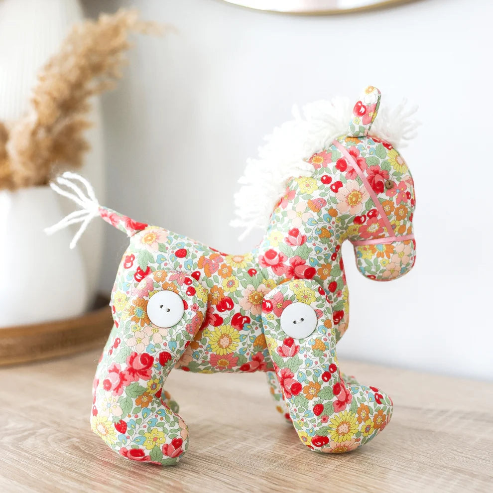 Floral-patterned plush horse toy on a white background