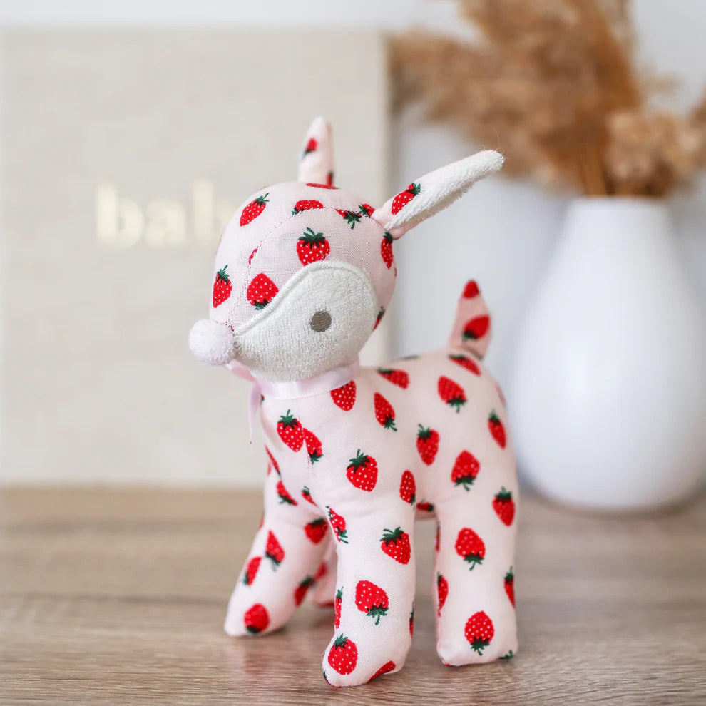 Plush toy deer with strawberry pattern on a wooden surface