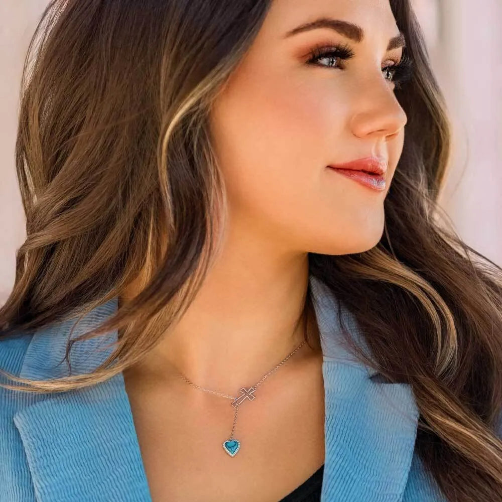 Woman wearing a necklace with a heart-shaped pendant against a neutral background