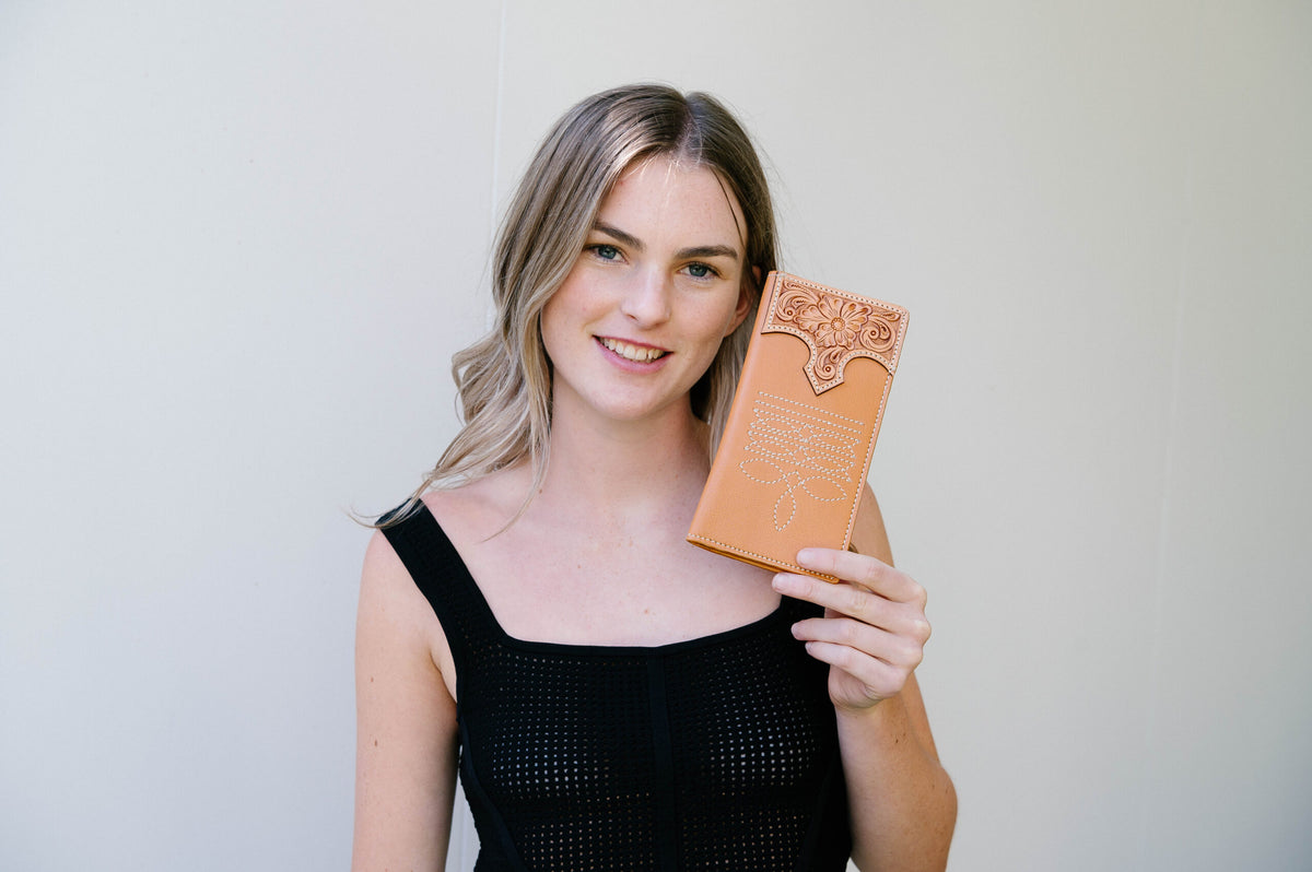 Woman holding a decorative brown book against a plain background