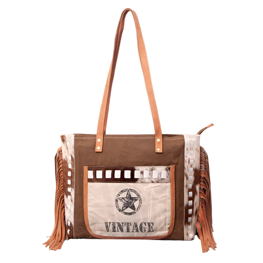 A brown and beige women's handbag with leather fringes and a 'Vintage' print on the front, featuring a star and the text 'American Darling'.
