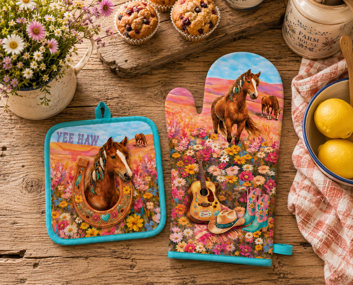 Two western-themed oven mitts and pot holders with a colorful floral field and horse design, styled on a rustic wooden table with muffins, flowers, lemons, and a jar.