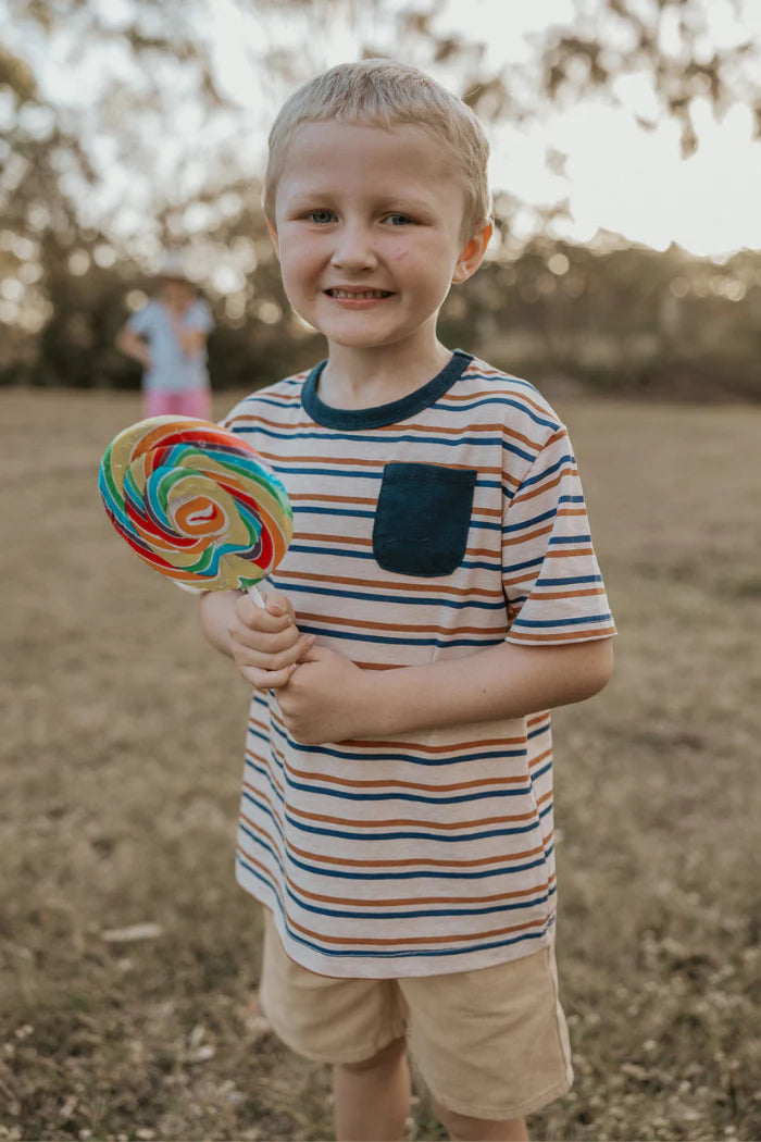 Milky Mini Stripe Pocket Tee. Young boy holding a large lollipop in an outdoor setting