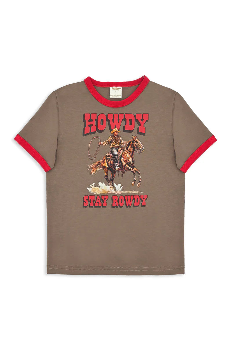 Milky Stay Rowdy Tee. Child wearing a cowboy hat and 'Howdy' shirt sitting on a wooden structure outdoors.