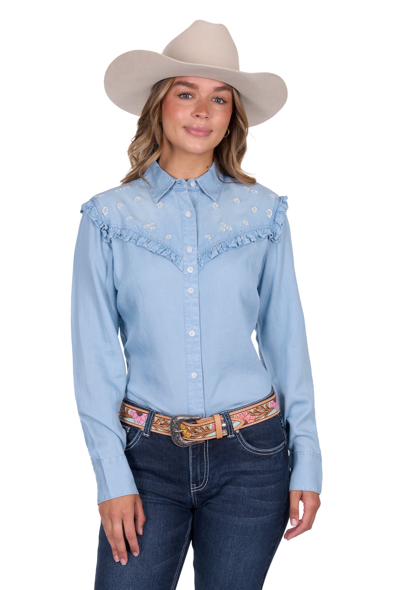 Pure Western Women's Phoebe L/S Western Shirt. Woman wearing a light blue denim shirt with embroidery, dark jeans, and a beige cowboy hat on a white background.