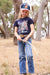 Pure Western Girl's Alesia Trucker Cap. Child in a natural setting wearing a navy t-shirt with a horse design and a cap.