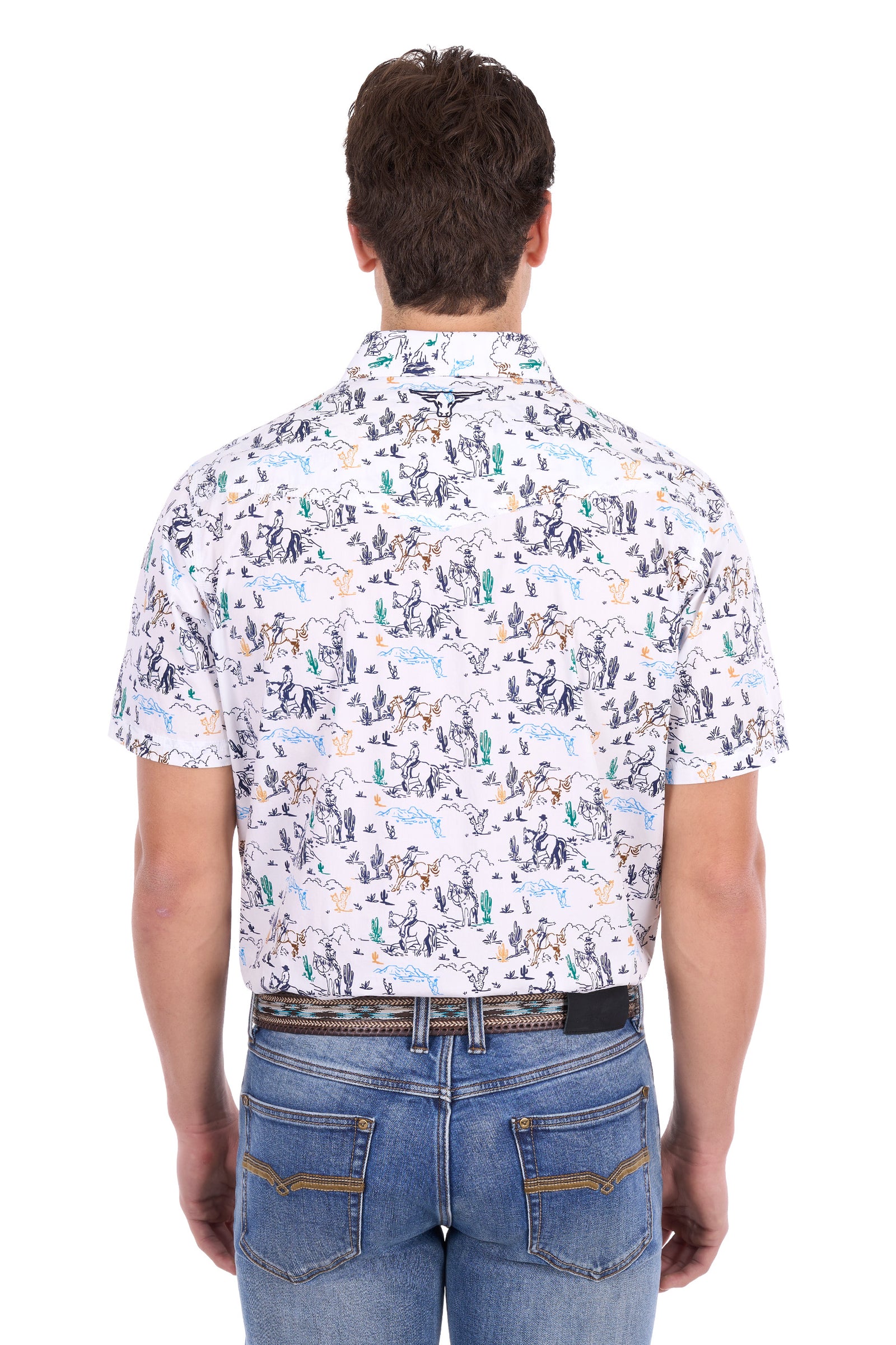 A man viewed from behind wearing a short-sleeve button-up shirt with a detailed desert animal and cactus pattern on a white base, paired with blue jeans.