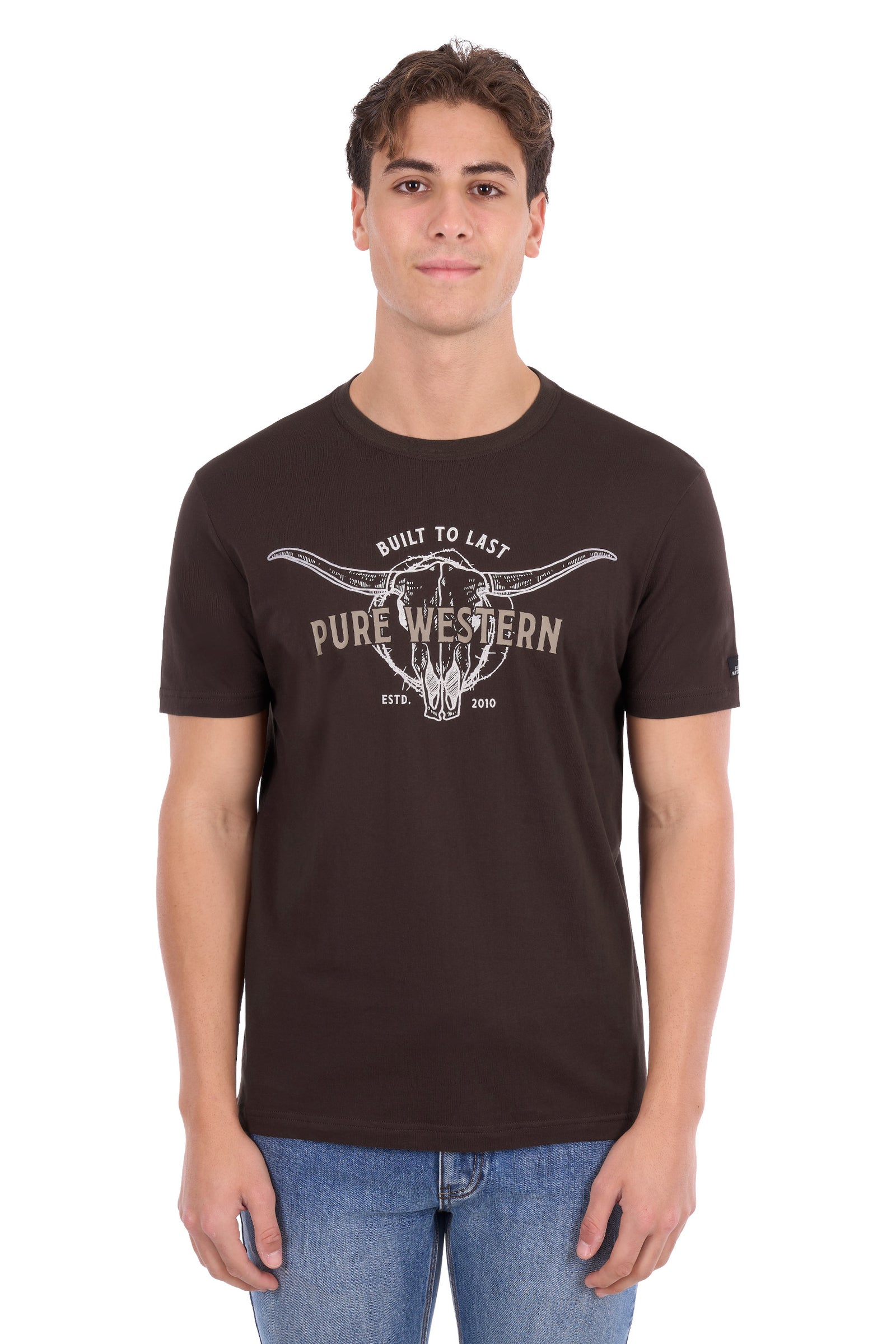 A man wearing a dark brown crewneck t-shirt with a white graphic print of a steer skull and the words 'PURE WESTERN' and 'BUILT TO LAST'.