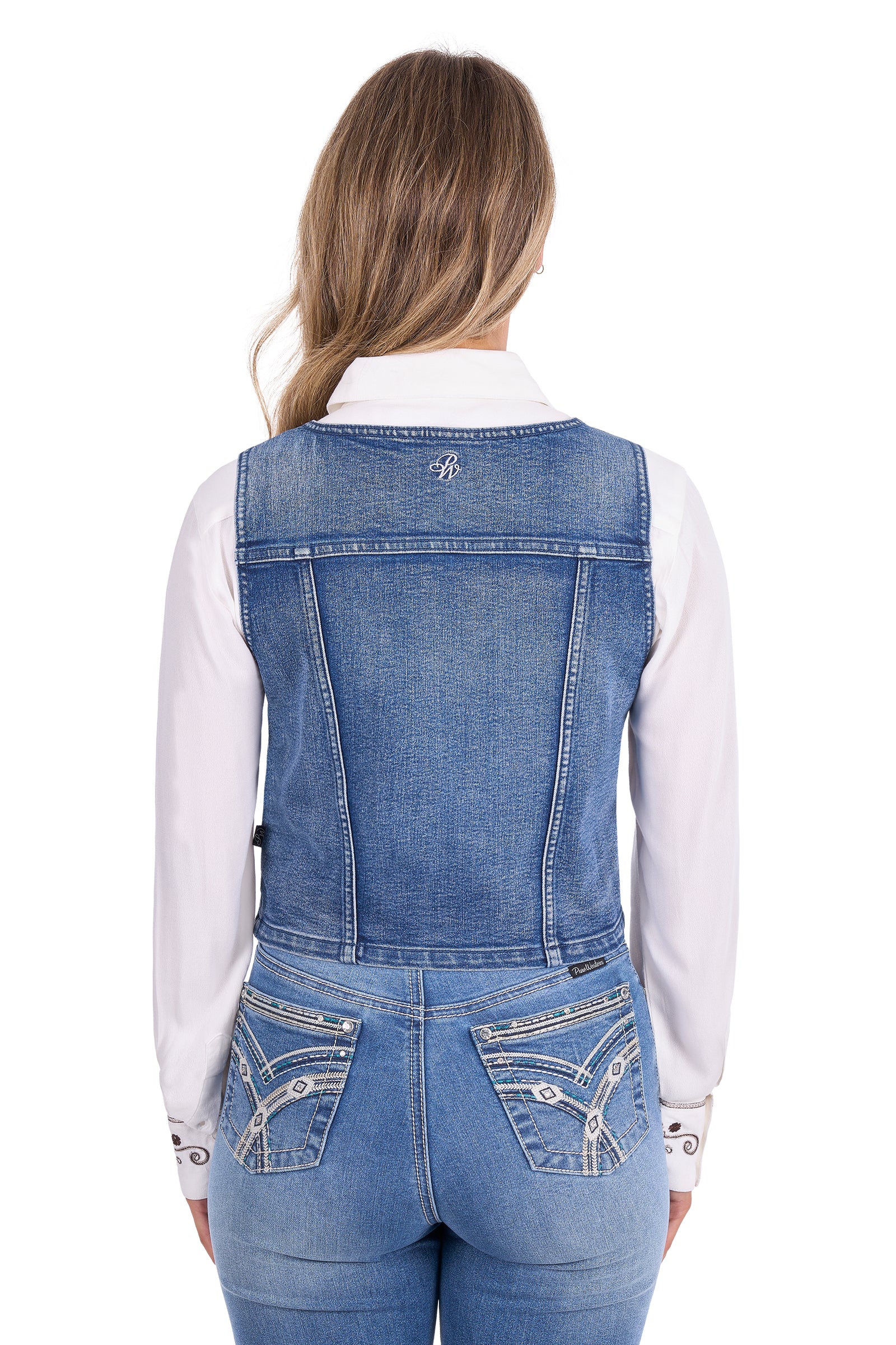 Rear view of a woman wearing a blue denim vest over a white long-sleeve shirt and blue jeans, against a plain white background.