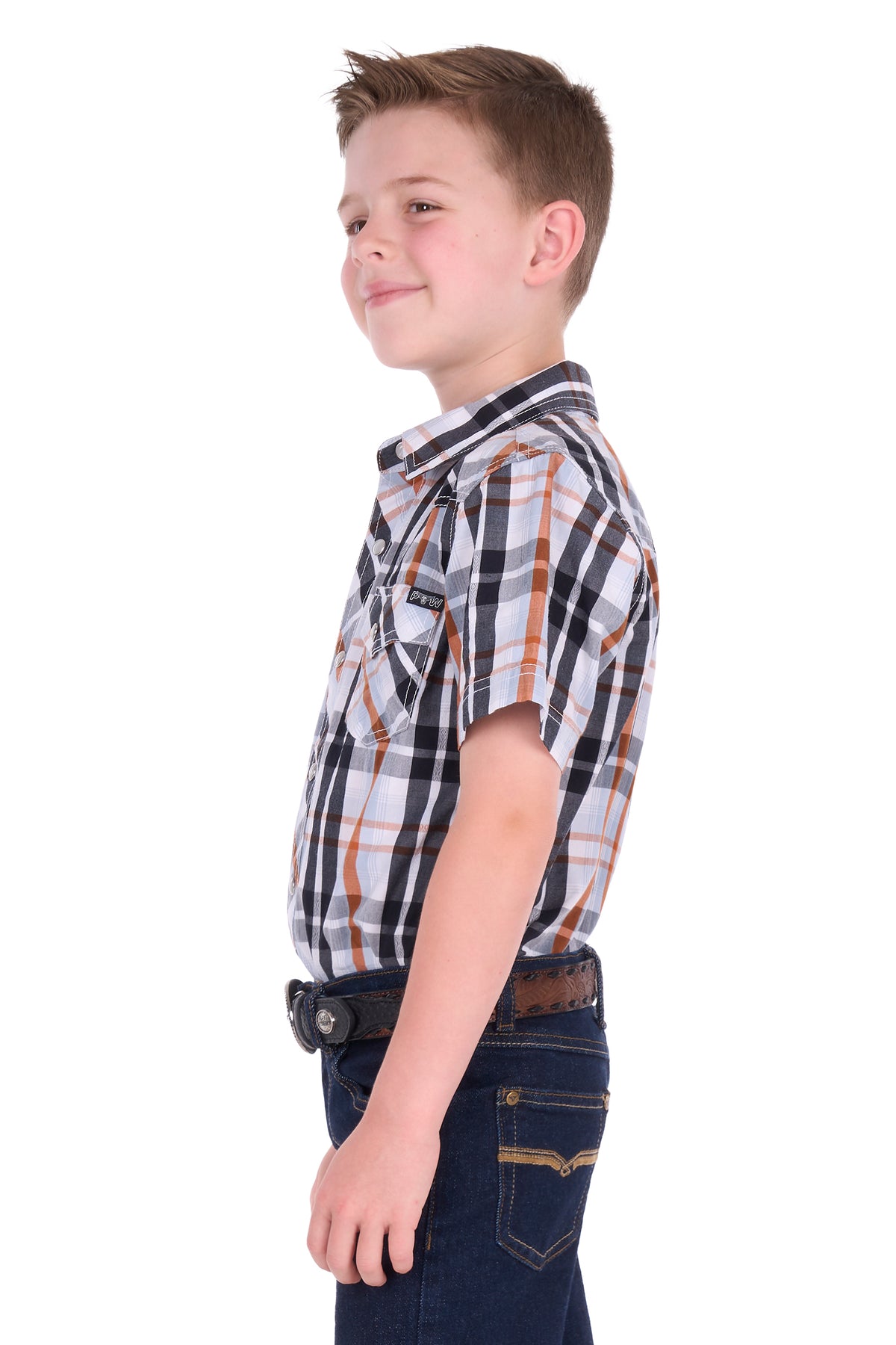 A young boy shown in profile wearing a short-sleeve plaid button-up shirt with dark blue jeans and a brown belt, photographed against a solid white background.