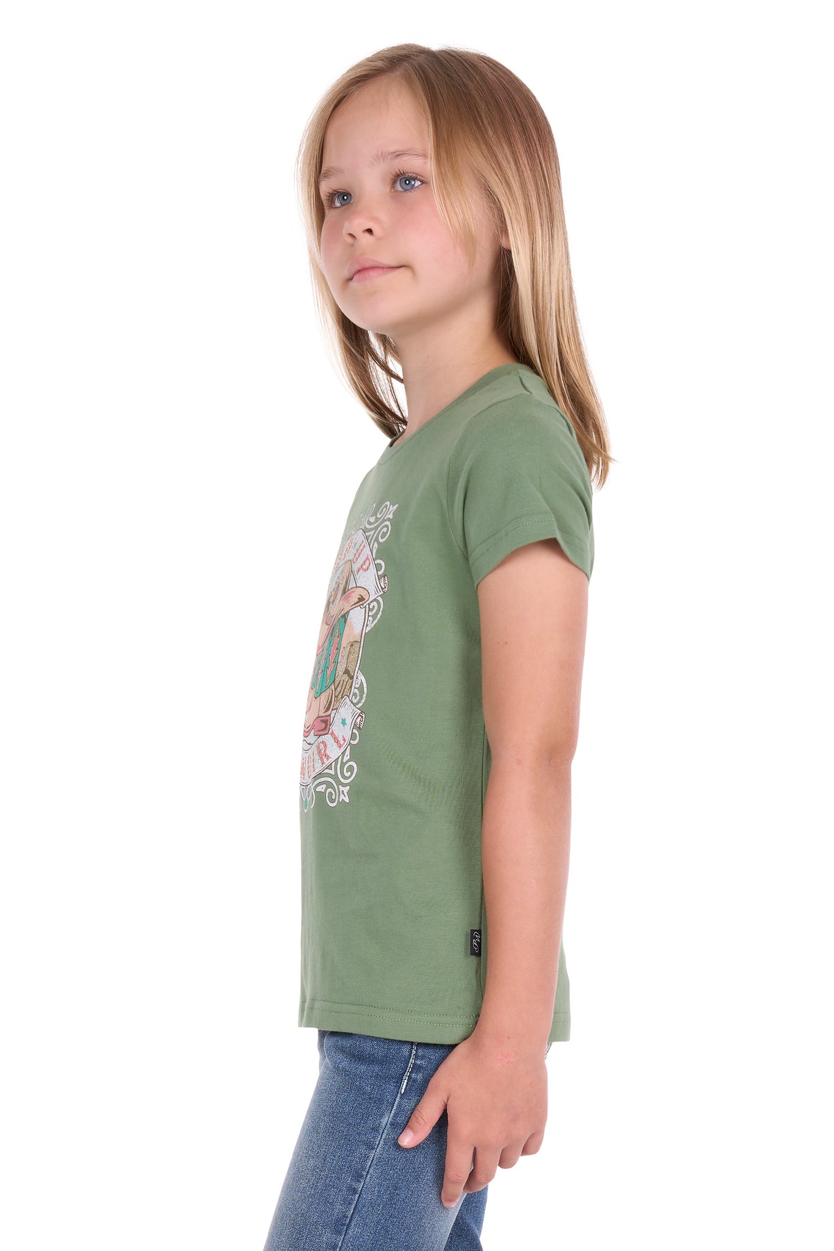 A young girl with blonde hair is shown in profile wearing a sage green short-sleeve t-shirt with a colorful graphic print on the front, paired with blue jeans, against a plain white background.