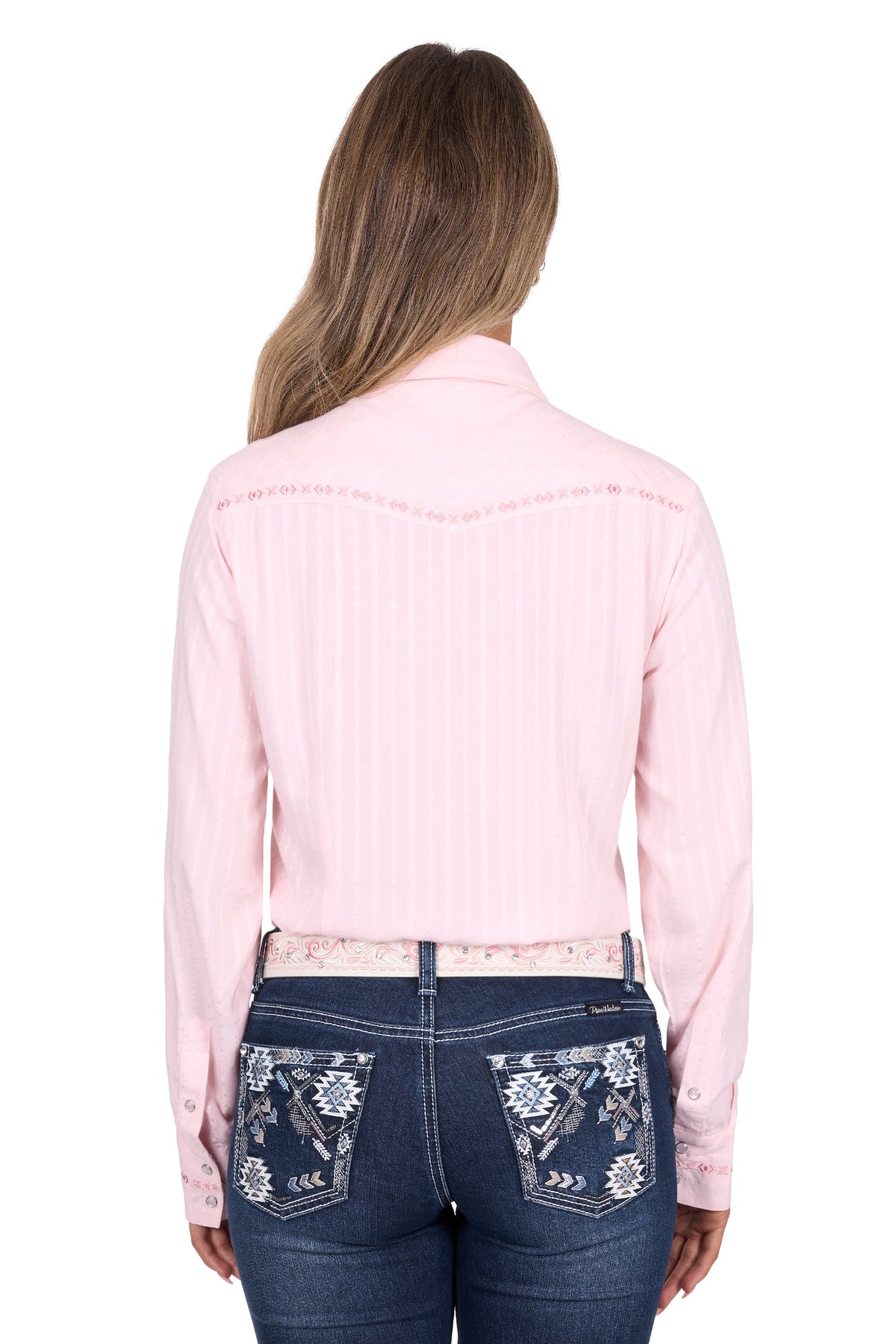 Woman wearing a pink long-sleeve shirt and blue jeans with floral embroidery on a white background