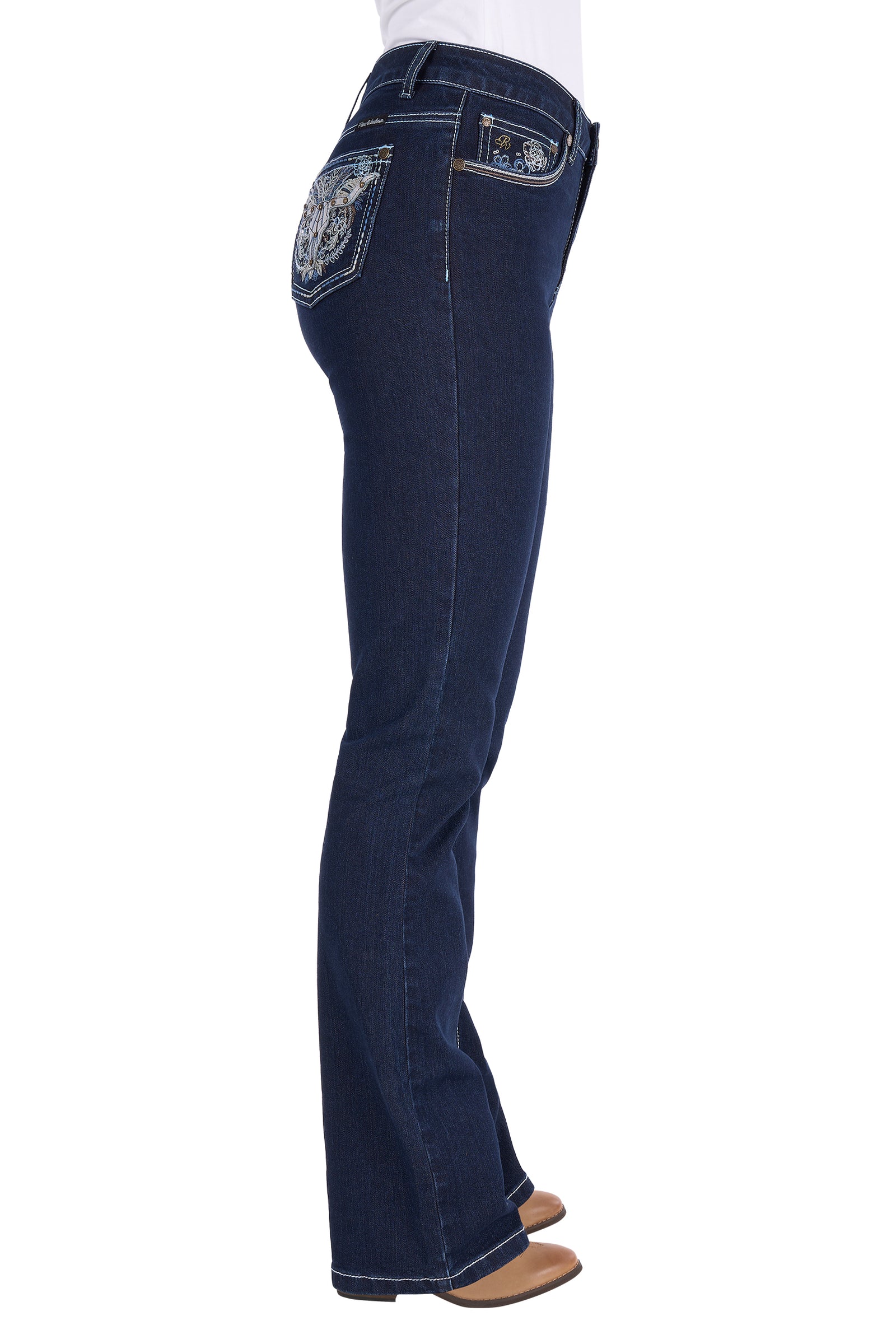 Side view of a person wearing dark blue flare jeans with decorative embroidered patches on the back pockets, paired with a white top and tan shoes, against a plain white background.
