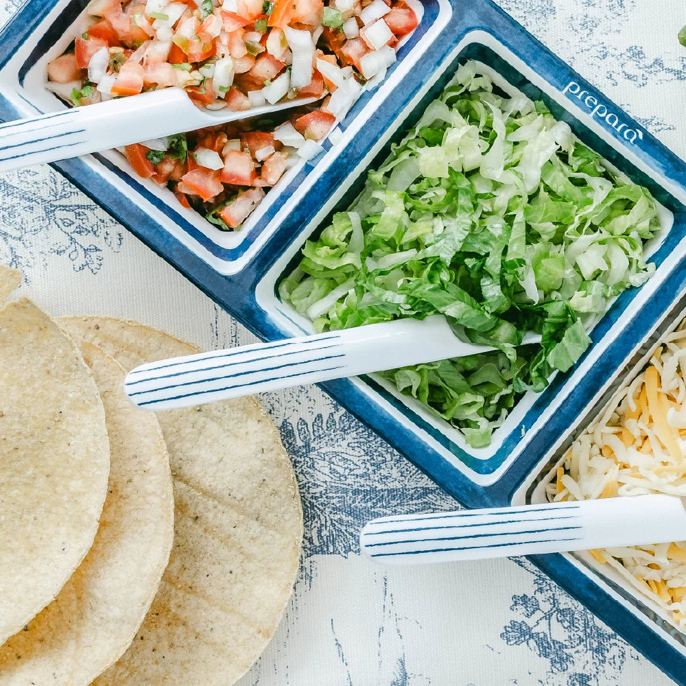 Tortilla chips with salsa, lettuce, and cheese on a blue and white patterned surface.