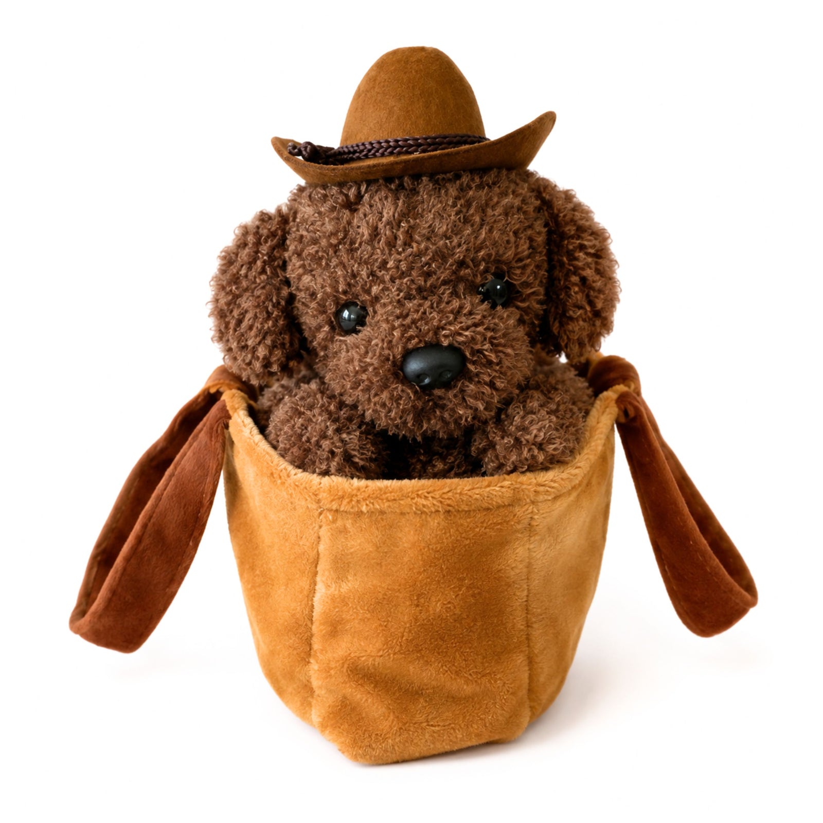 A brown plush dog toy wearing a tan cowboy hat and sitting inside a tan plush bag with long hanging ears, photographed on a clean white background.