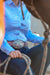 Reba Women's Blue Bird Oxford Gal L/S Shirt. Person wearing a blue shirt and jeans with a decorative belt, holding rope.