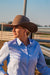 Reba Women's Blue Bird Oxford Gal L/S Shirt. Person wearing a brown cowboy hat and blue shirt outdoors